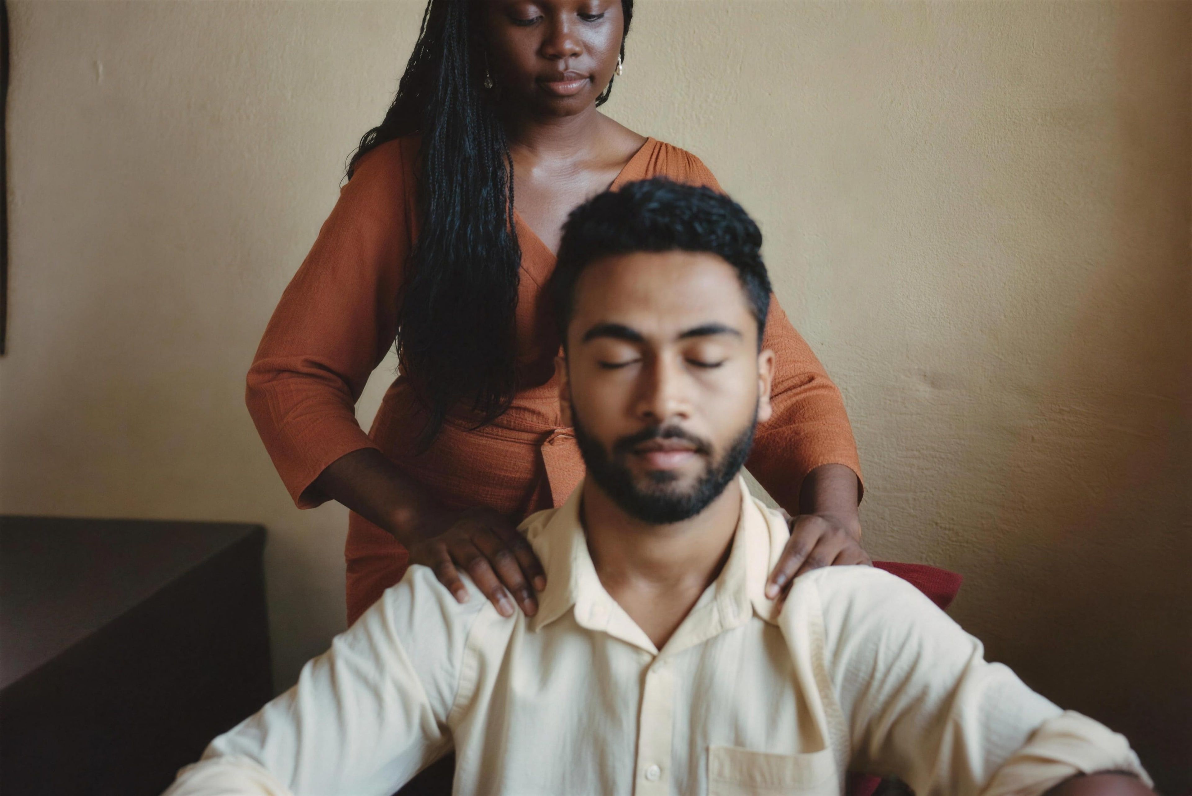 An energy healer resting her hands on the shoulders of a seated man