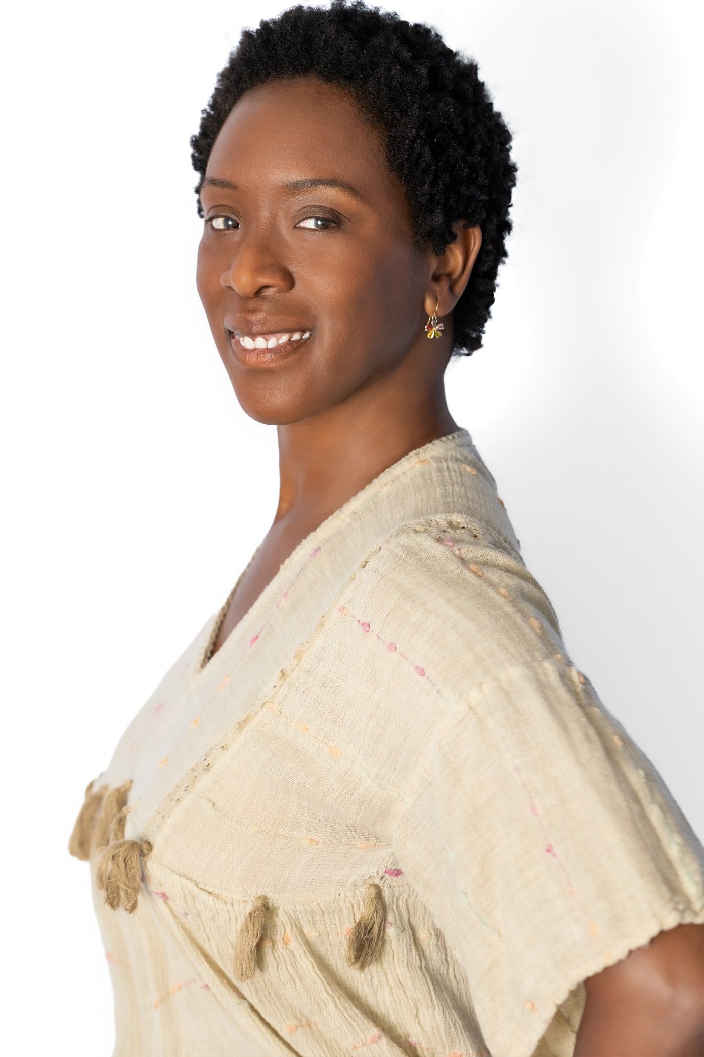 Yolessa smiling over her shoulder in a cream linen dress